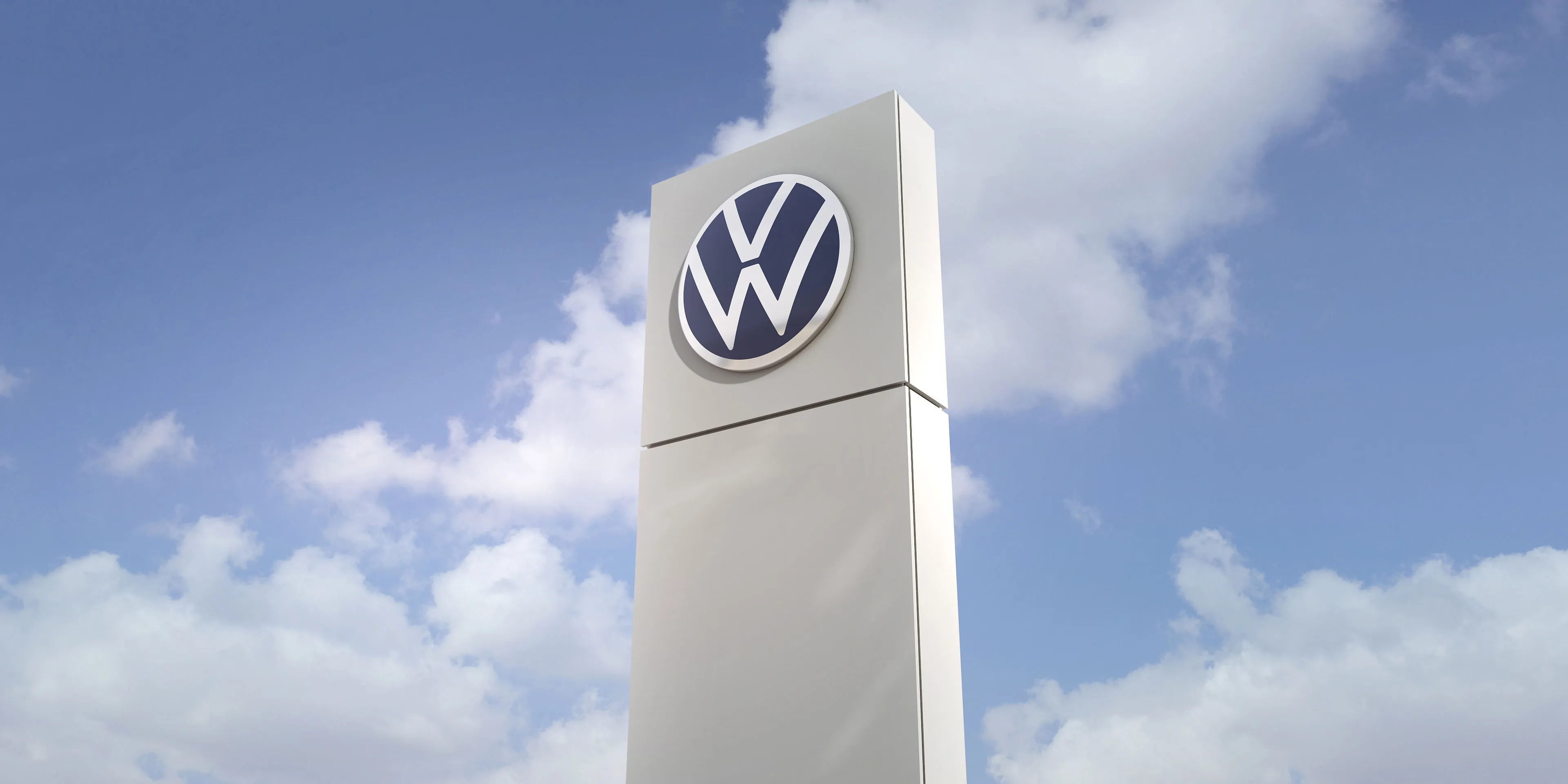 Säule mit Volkswagen Logo mit Himmel im Hintergrund.