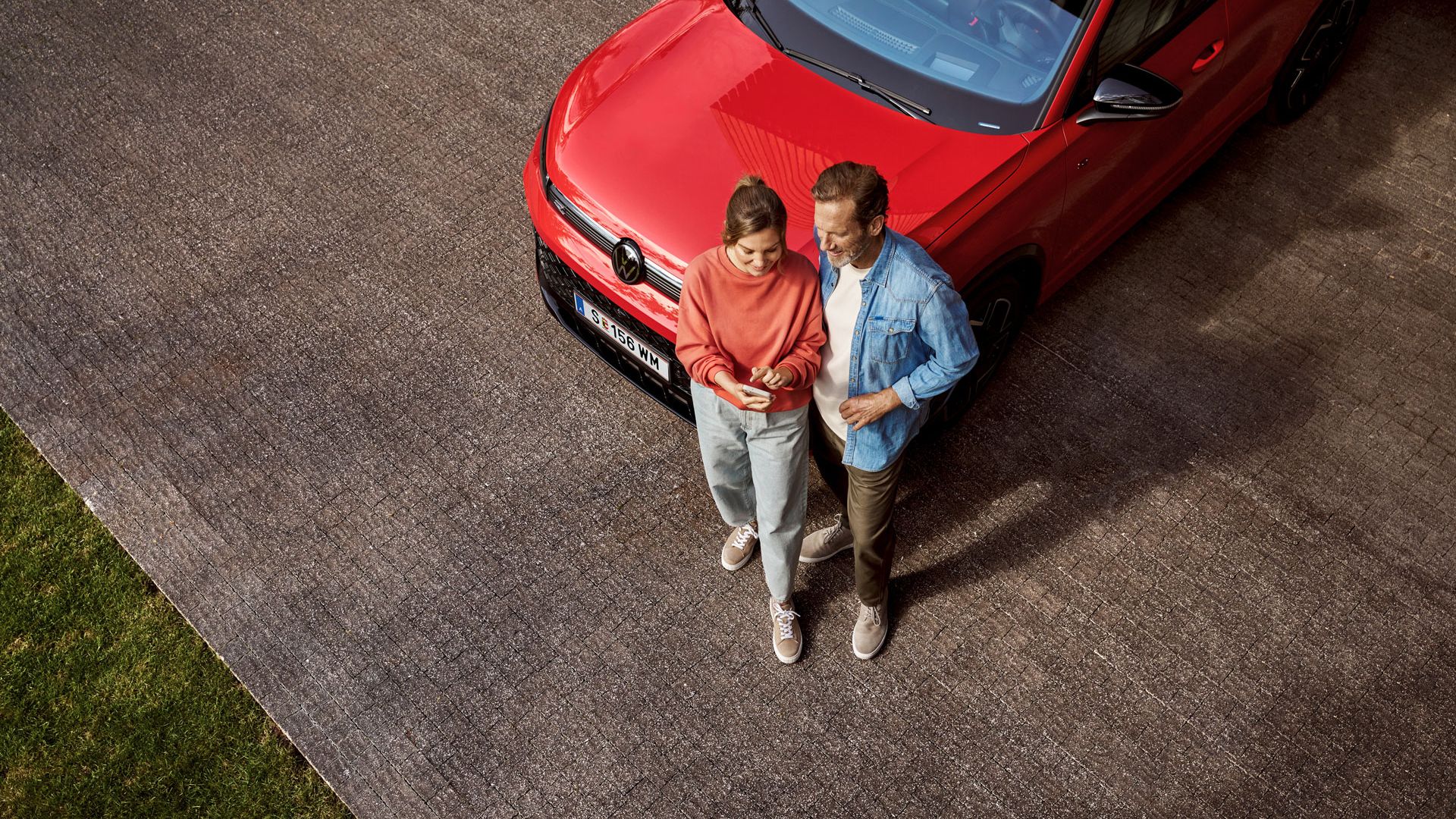 Ein Paar steht vor dem Tiguan und schaut auf das Handy.